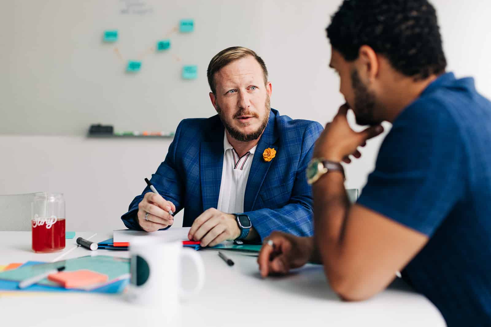 Two men discussing ideas at table.